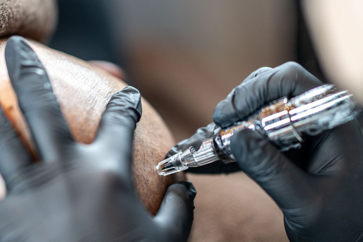A scalp tattoo artist conducting a demonstration during a tattoo and permanent make up contest in Naha, Okinawa prefecture. - AFP