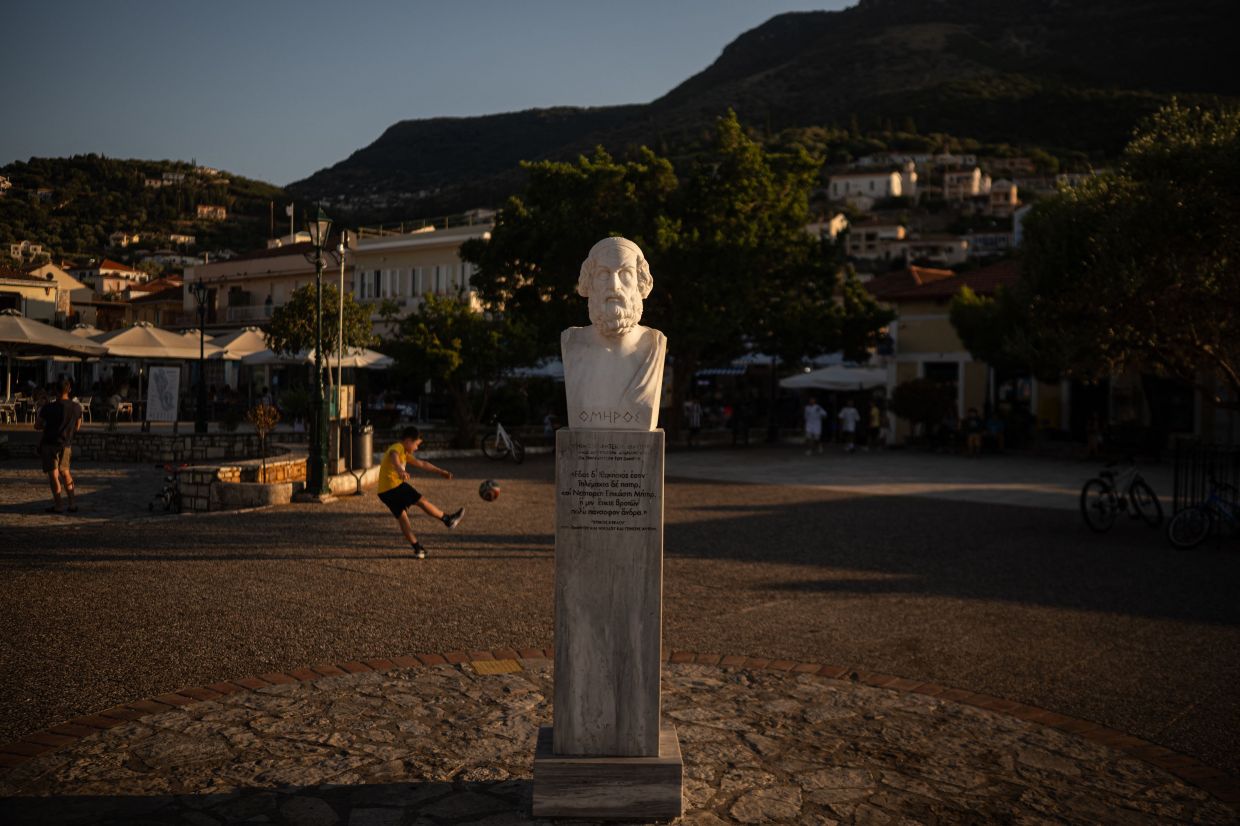A child plays football next to a marble bust of ancient Greek poet Homer in the central square of Vathy, on the island of Ithaca, in the Ionian Sea. Photo: AFP