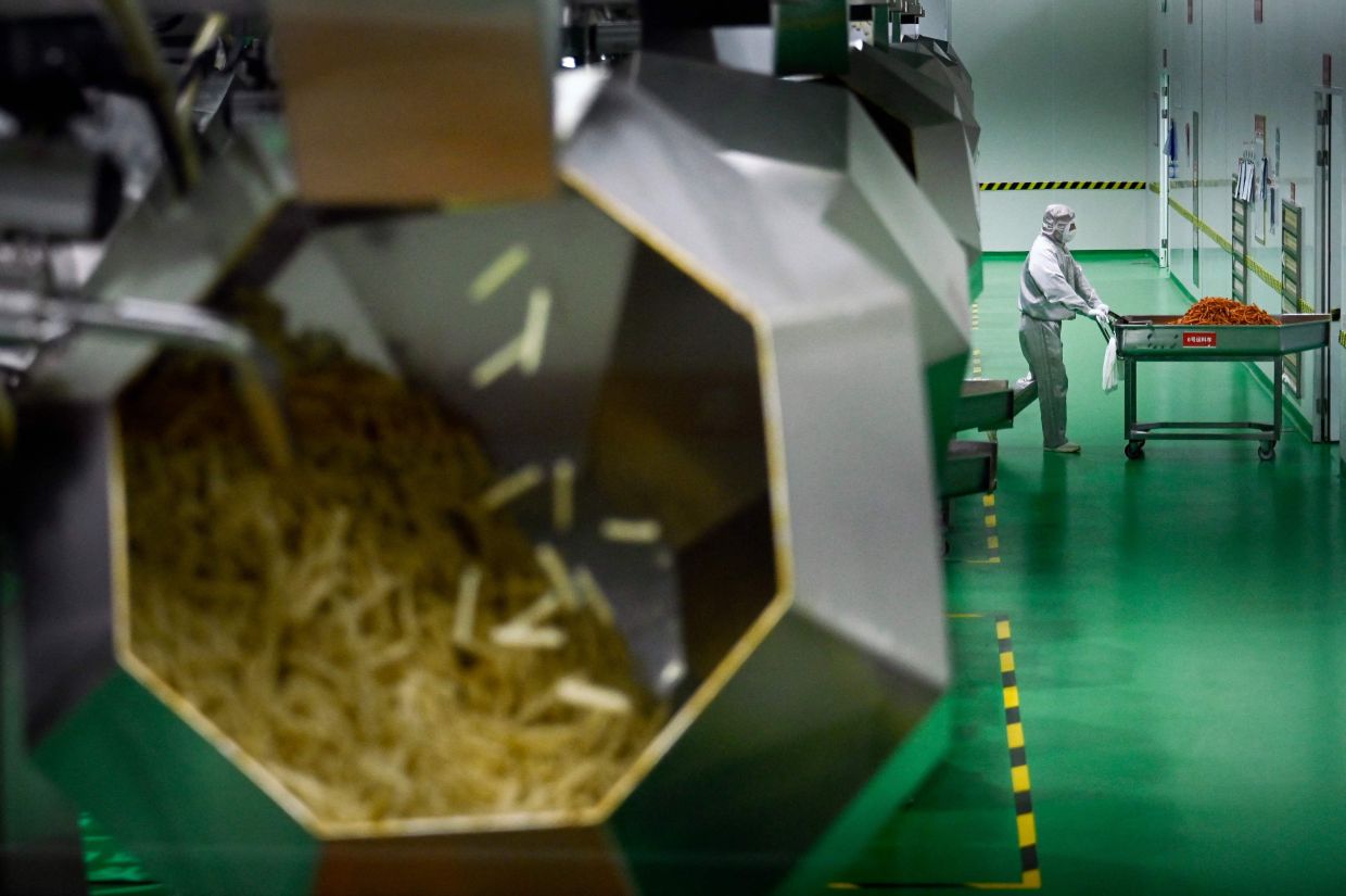 A workertransporting spicy strips to the packaging area at the Mala Wangzi factory in Pingjiang county, in China's central Hunan province.