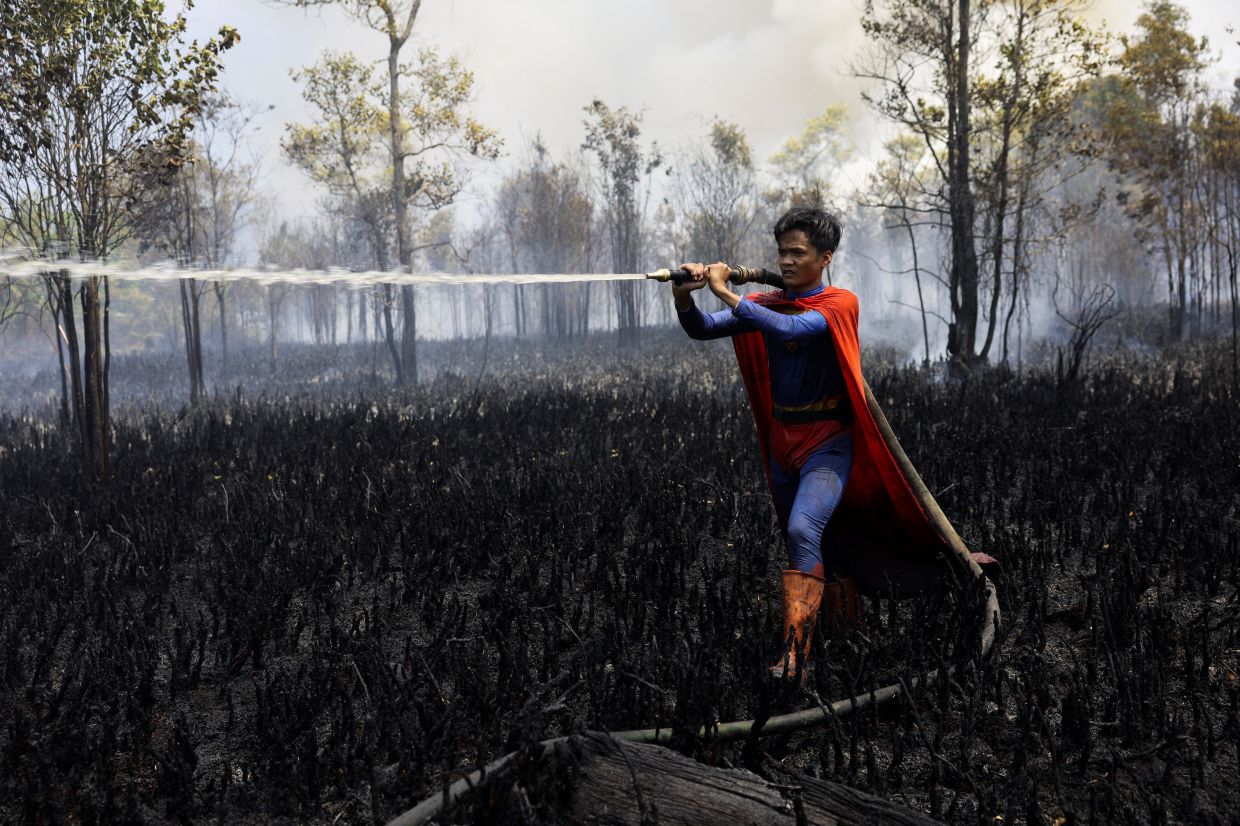 Rudiyansah, 16, wearing a Superman costume while extinguishing a fire at a wildfire-affected area in Palangka Raya, Central Kalimantan province, Indonesia on Augt 14, 2026. - Reuters