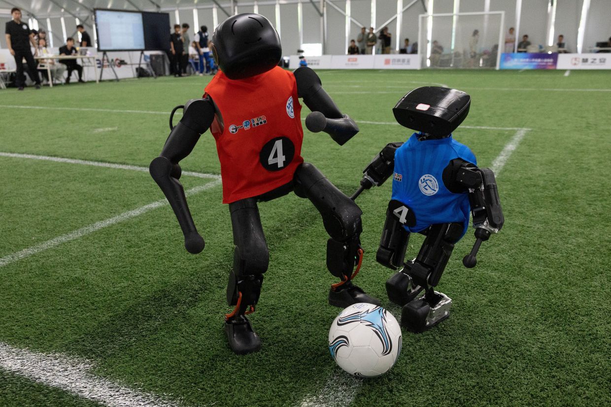 Humanoid robots fighing for the ball during a football match in a media preview ahead of the World Humanoid Robotic Games in Beijing, China on Aug. 14, 2026. - AP