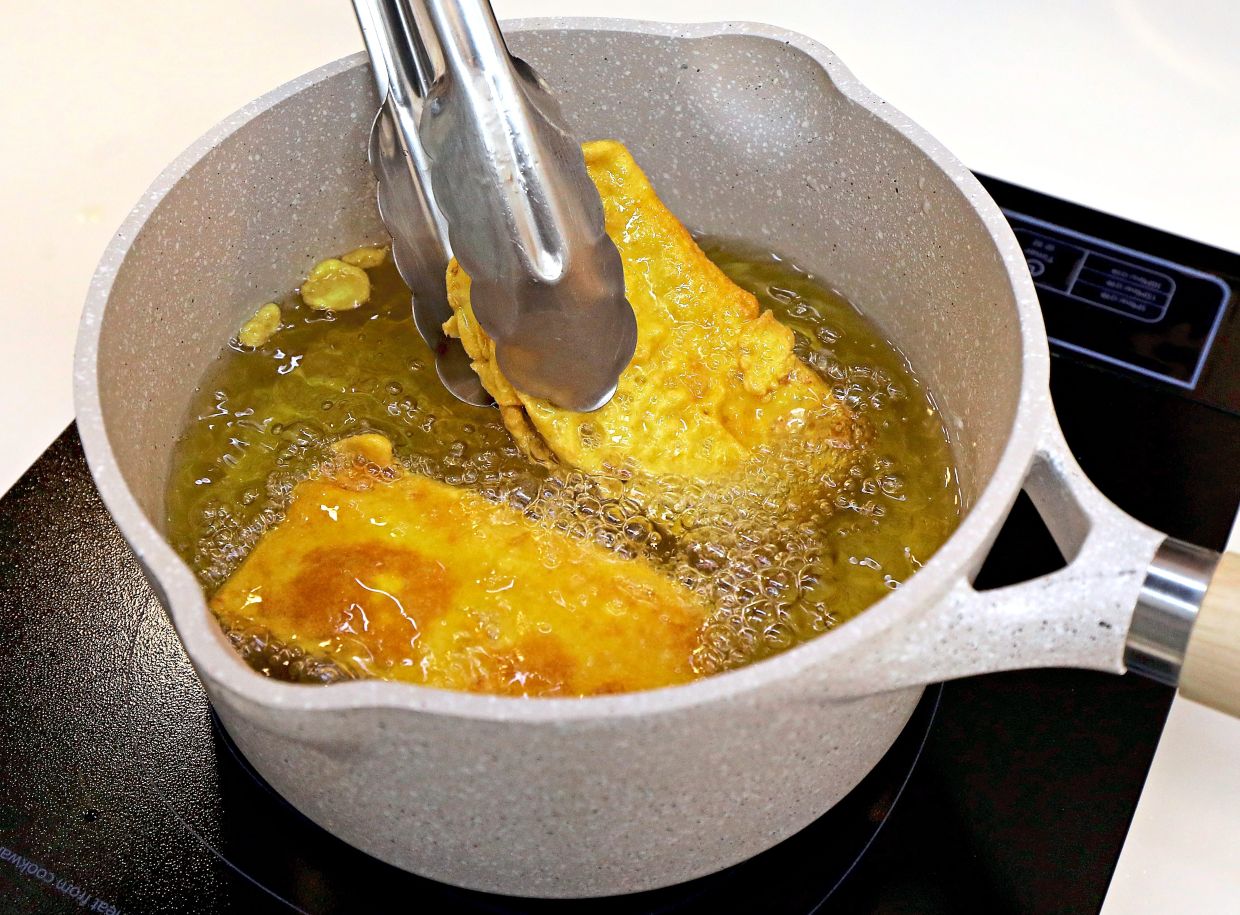 Deep fry the batter-filled tempeh pieces until golden.