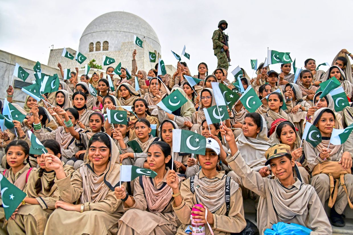 Green and white pride: Students waving national flags during an Independence Day ceremony at the mausoleum of Pakistan’s founder, Muhammad Ali Jinnah, in Karachi. — AP