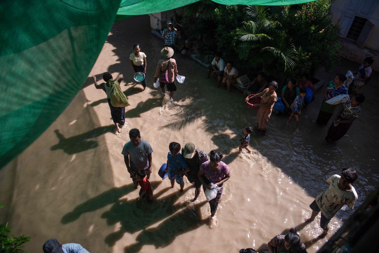 Residents wade through floodwaters in Wetlet, Myanmar's Sagaing region, on Friday, August 14, 2026. -- Photo by AFP