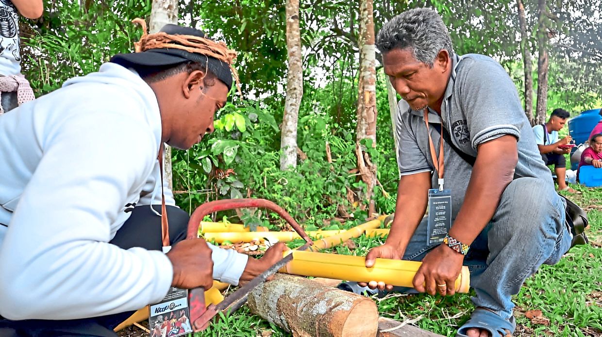 Participants preparing food using bamboo during a traditional cooking activity, where communities shared their dishes and cooking methods with one another. 