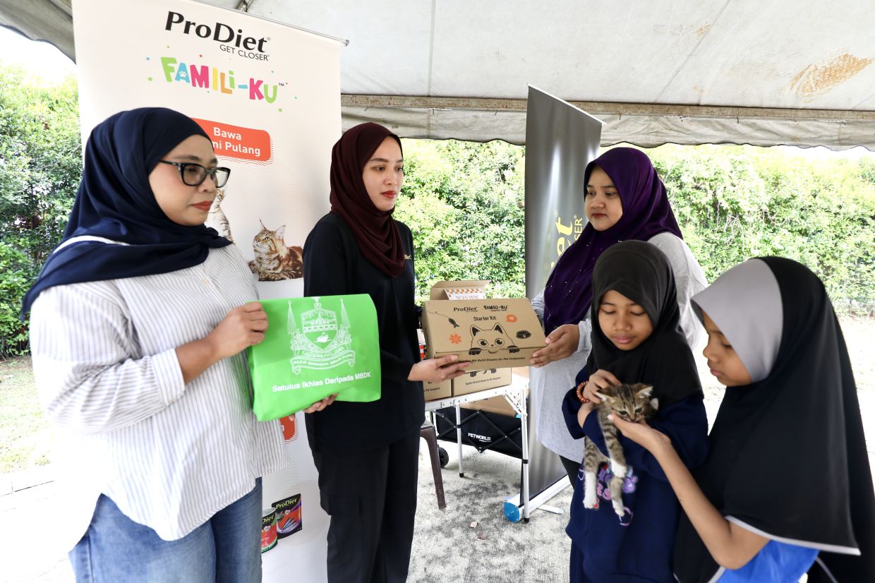 Above: Taman Kucing Klang in Bandar Bukit Raja will hold another cat adoption event in October. Left: (From left) Nurbaiti and Pet World Nutritions Sdn Bhd officer Izhaty Khiarudin handing over cat adoption items to Jamaliah Rahman and daughters Fitri Amara Aisyah and Fitri Amara Aliesyah at the event.