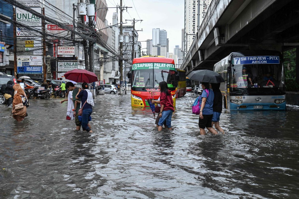 Commuters cross a flooded street triggered by heavy monsoon rains in Manila on Monday, August 17, 2026. -- Photo by Ted ALJIBE / AFP