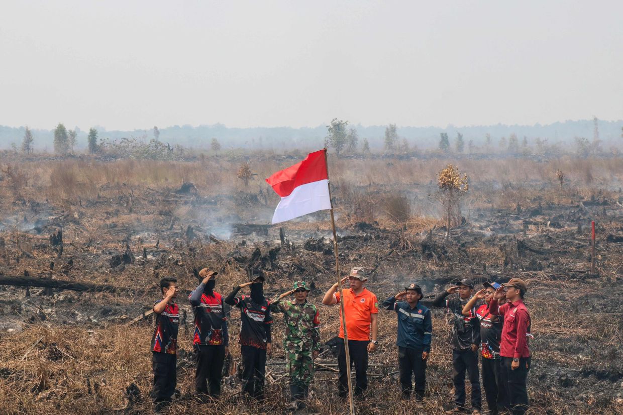 Firefighters take a moment to commemorate Indonesia's 81st Independence Day by hoisting the national flag in an area affected by forest and land fires in Palangka Raya, Central Kalimantan, on Monday, August 17, 2026. -- Photo by REINA / AFP