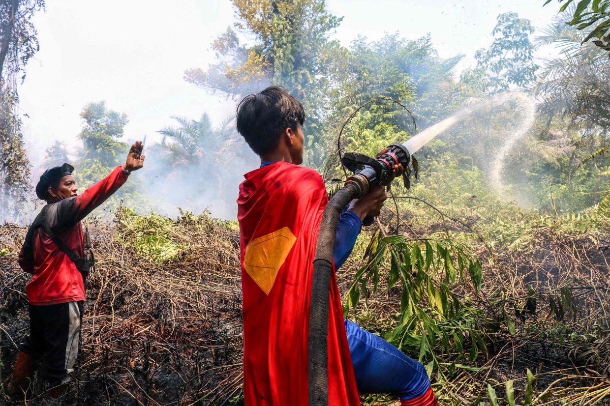 Indonesian student Rudiansyah (right) dressed in a Superman costume, helps to extinguish a forest and land fire at Petuk Katimpun in Palangka Raya, Central Kalimantan, on Monday, August 17, 2026. -- Photo by REINA / AFP