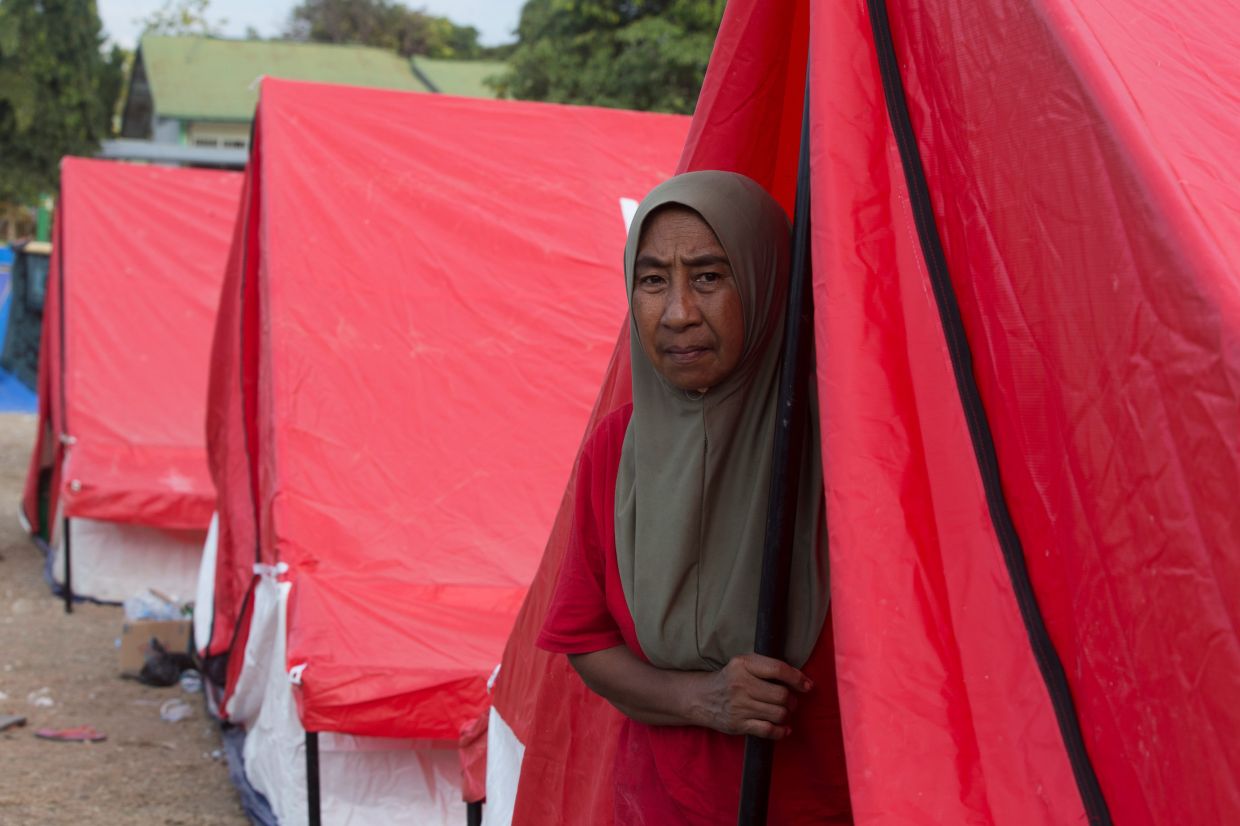 A woman looks out from a temporary shelter for earthquake survivors in Reo, East Nusa Tenggara province, Indonesia, on Monday, Aug. 17, 2026. -- AP Photo/Firdia Lisnawati