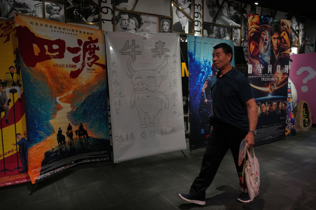 A man walks by a drawing poster promoting a Chinese animated film 'Niulai' on display with other movie posters at a cinema in Beijing, Tuesday, Aug 18, 2026. Photo: AP