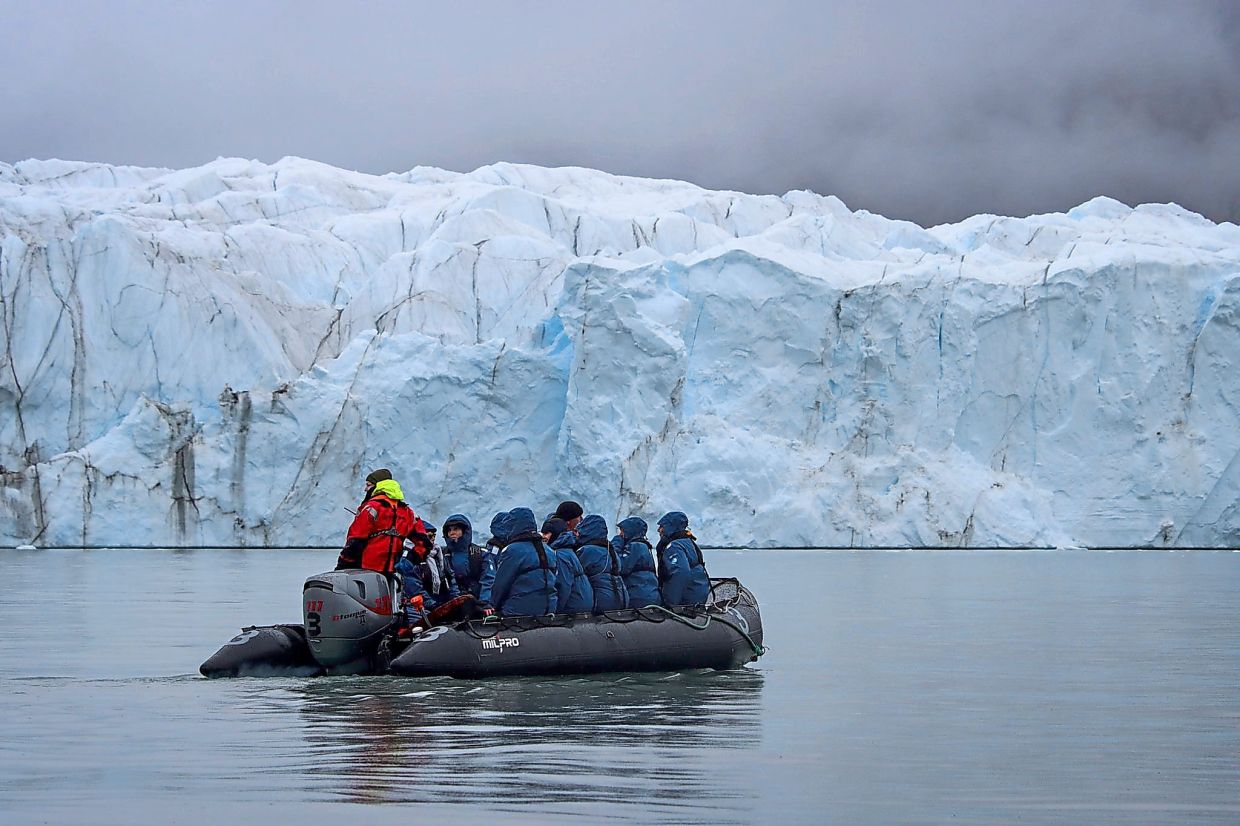 Guests hop into a dingy to reach land from the expedition ship off Greenland.
