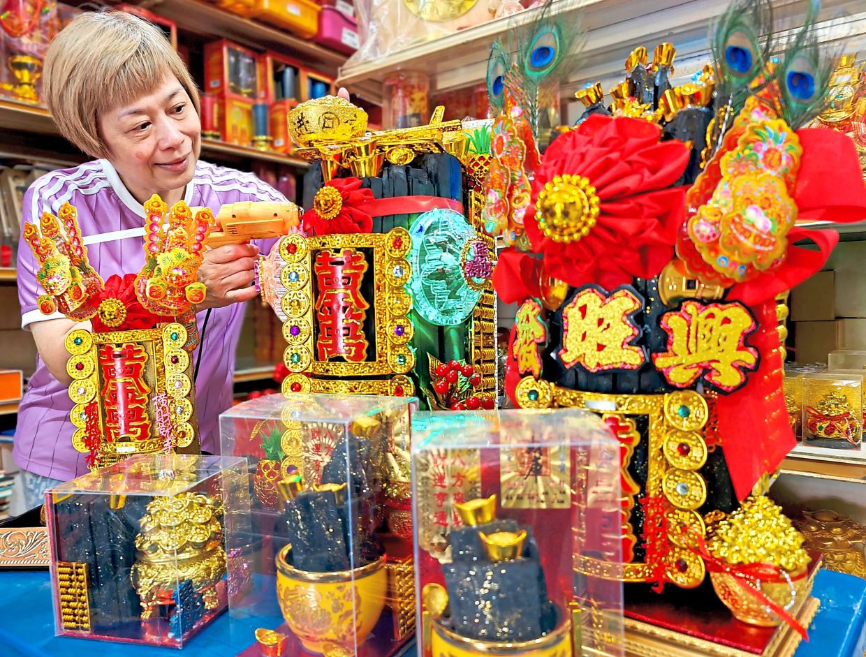 Worker Angeli Choo standing next to pieces of ‘black gold’ at a prayer paraphernalia shop in Jalan Rangoon, George Town. — KT GOH/The Star