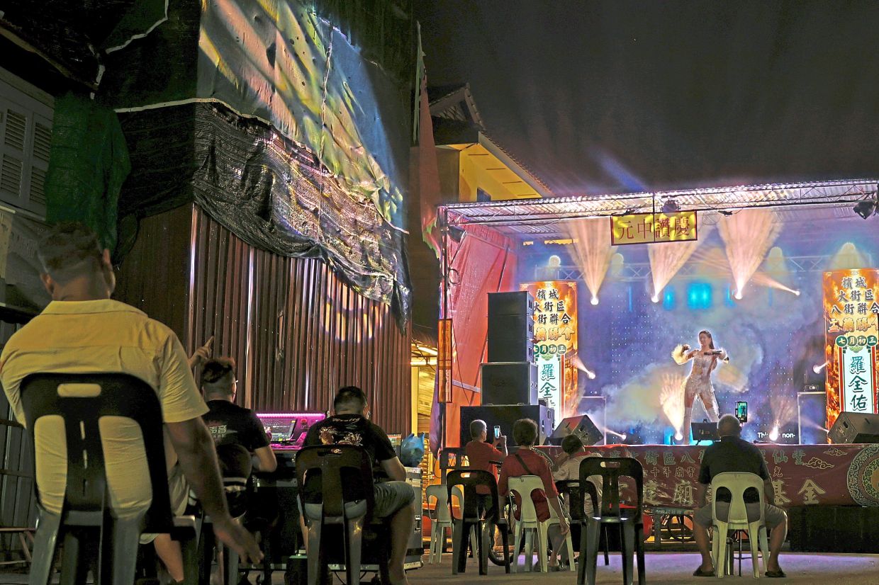 A singer belting out a song on a brightly lit stage during a live stage show forHungry Ghost Festival along Queen Street in George Town.