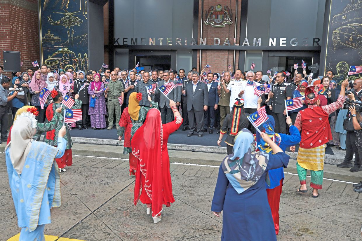 Patriotic spirit: Saifuddin Nasution (centre) waving the Jalur Gemilang while enjoying a dance performance at the National Month celebration at the Setia Perkasa Lobby, Home Ministry in Putrajaya. — Bernama