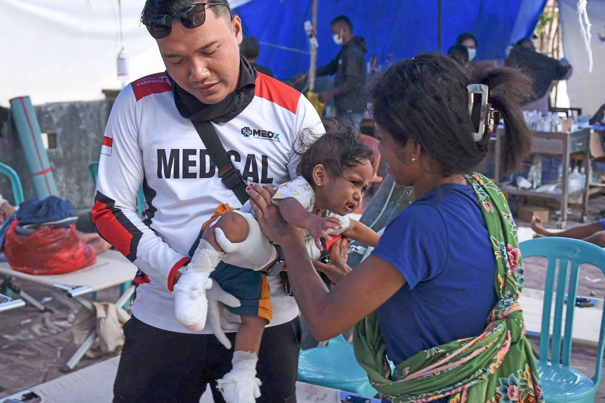 A medical worker in East Manggarai checking up on an infant injured in the quake. — Agencies