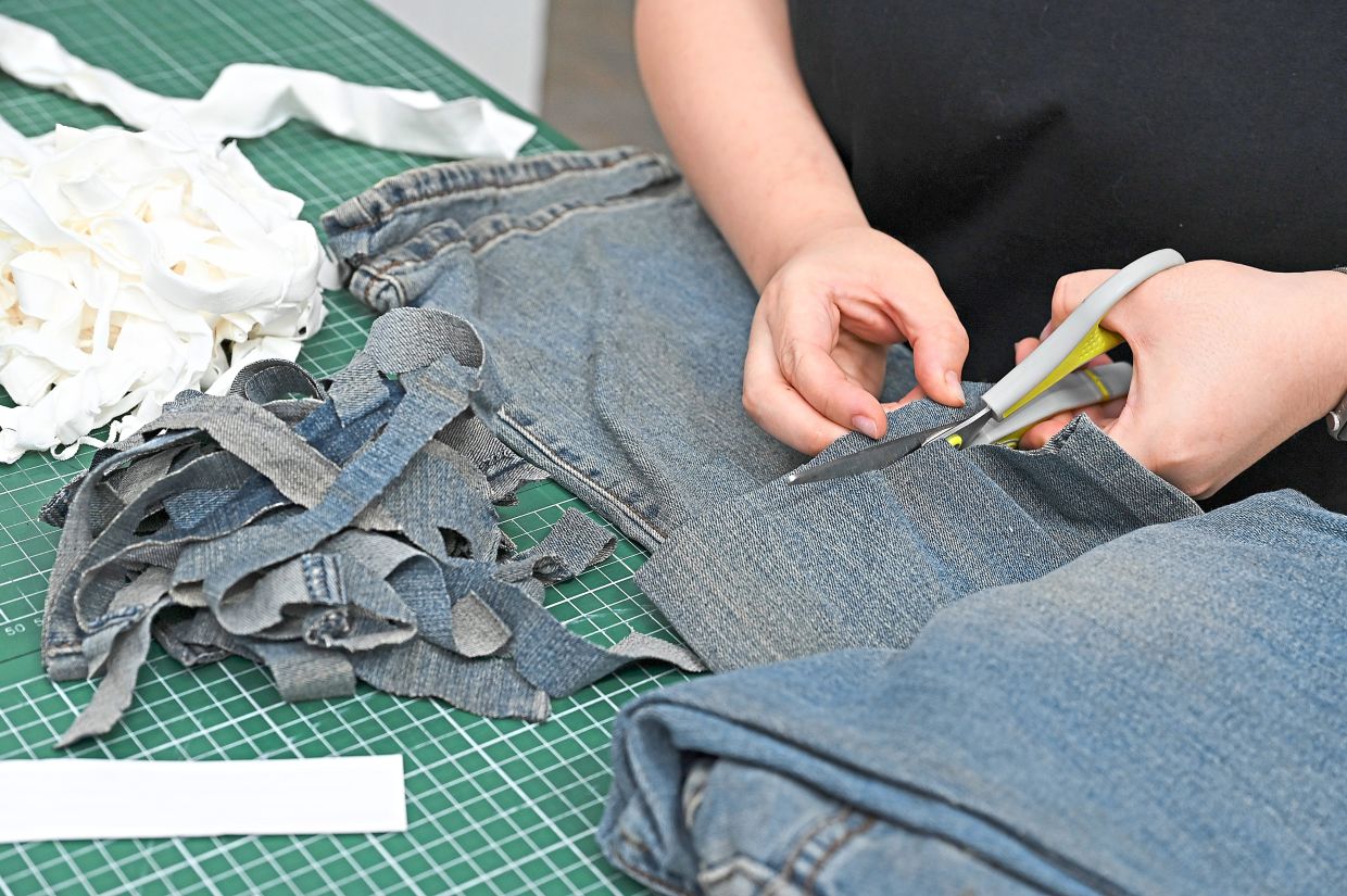 Old jeans being cut into smaller pieces before getting a new life as paper.