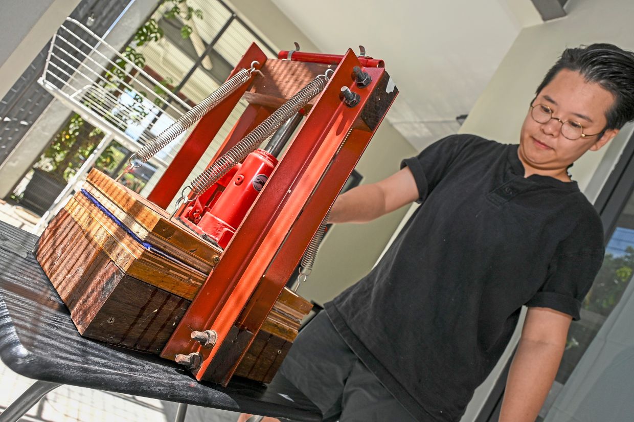 Soo uses a hydraulic press to squeeze out the excess water and compress the paper sheets.