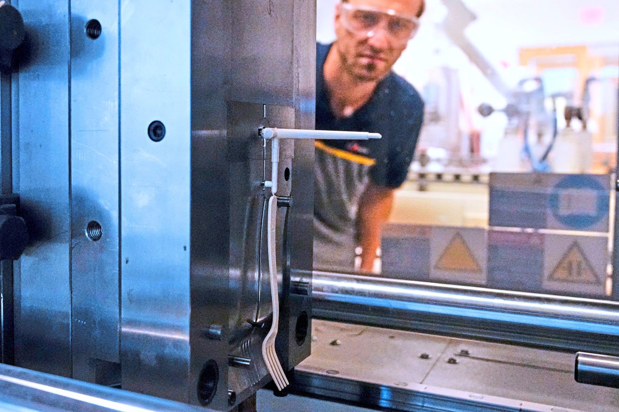 Polymer engineer Peter Steeves watches a compostable fork being moulded in a testing laboratory in Woburn.