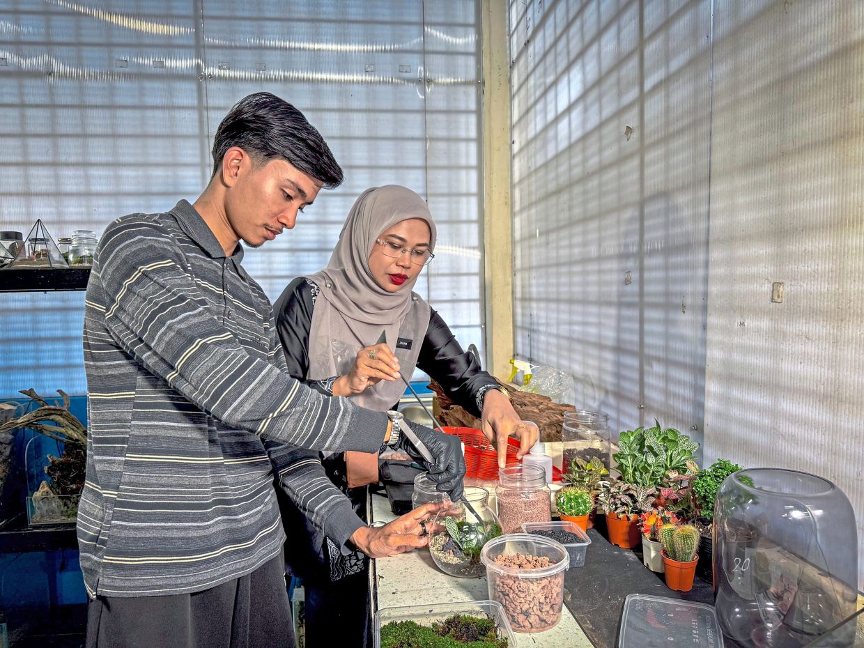 Muhammad Syukur working with Green Vista Club adviser Zalina on a terrarium at the technical institute in Jeli, Kelantan.
