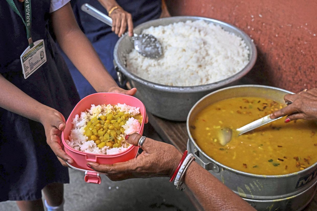 A student receives a mid-day meal at a government primary school in Kolkata on July 9, 2026. The humble egg, a popular food in West Bengal, was taken off the menu on June 2026 after the state's recently elected Hindu nationalist government said a religious charity will provide free, vegetarian cooked meals in state-run schools. The new arrangement has rekindled a long-running debate over food, faith and nutrition in the world's most populous country, with critics accusing the government of trying to turn schoolchildren vegetarian. (Photo by Dibyangshu SARKAR / AFP)