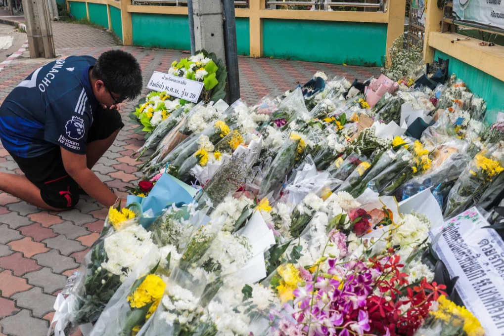 A student of Debsirin Nonthaburi School leaves flowers outside the school on Aug 11 following a deadly shooting four days earlier. - Reuters