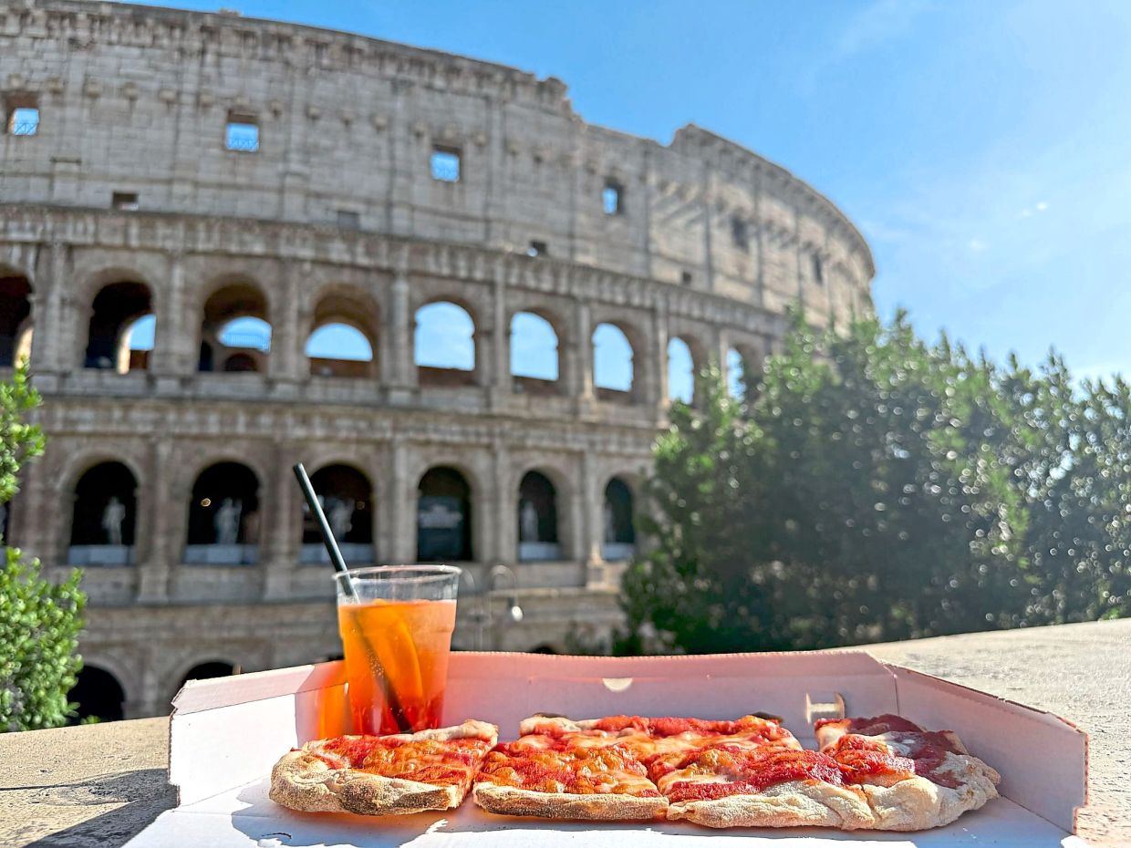Though usually enjoyed as an aperitif, some will wash an Aperol down with a pizza, as seen here in front of the Colosseum. — SABINA CRISAN/dpa