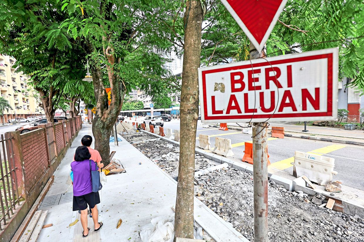 Visually impaired pedestrians using the completed 1.3m-wide walkway along Jalan Sultan Abdul Samad in Brickfields, while work on the adjoining bicycle lane project continues.