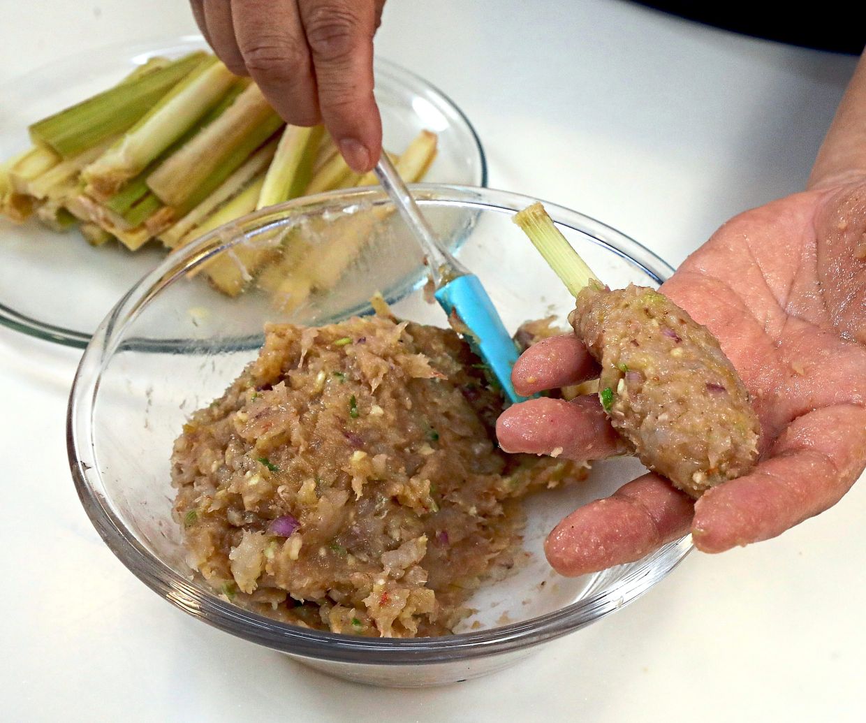 With wet hands, mould the prawn paste around the sugarcane stick, then set aside in the refrigerator to firm up.
