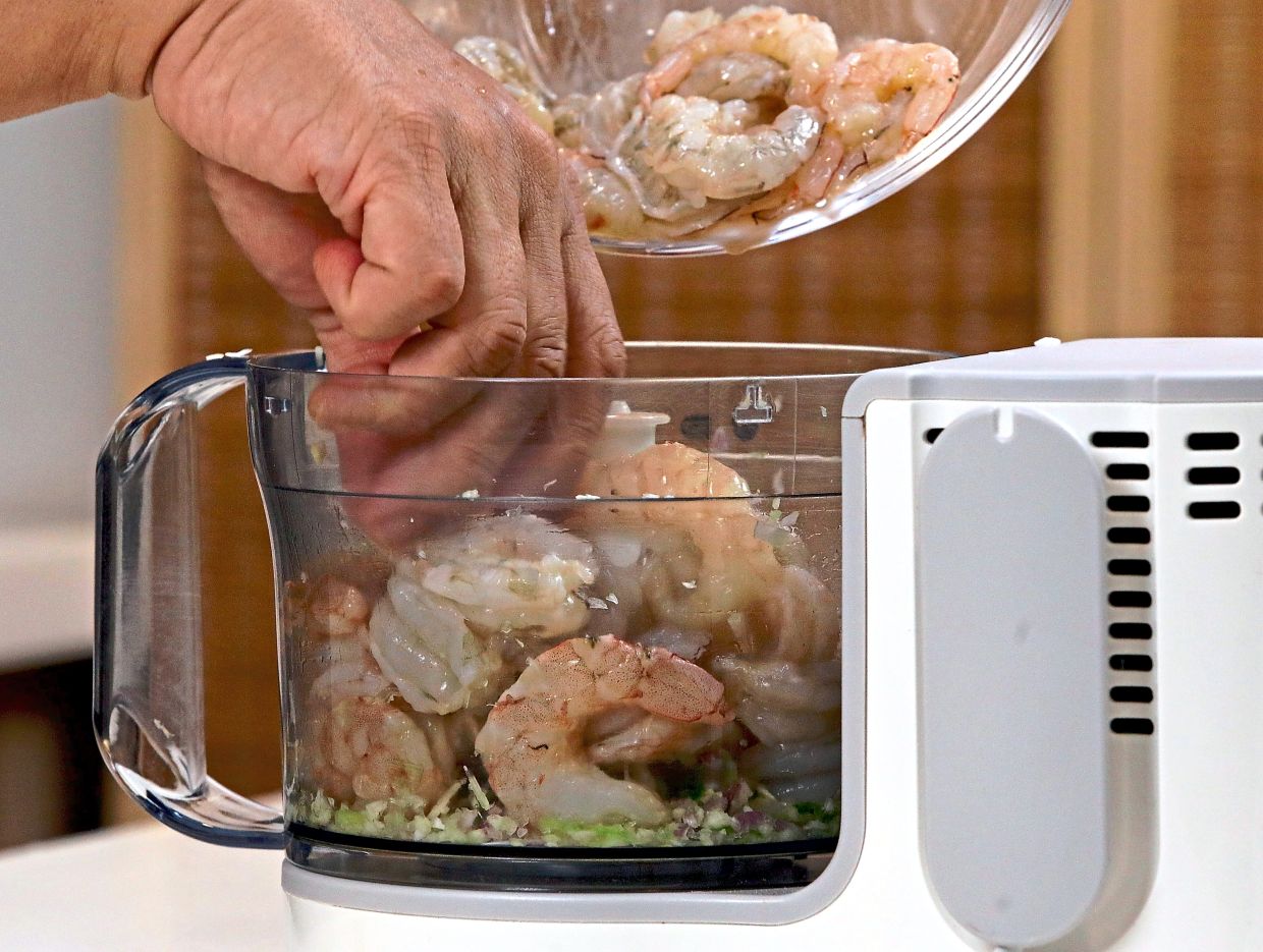 Mince shallots, garlic and spring onions in a food processor, then add prawn meat, rice flour, sugar, fish sauce and pepper, and pulse until coarsely chopped.