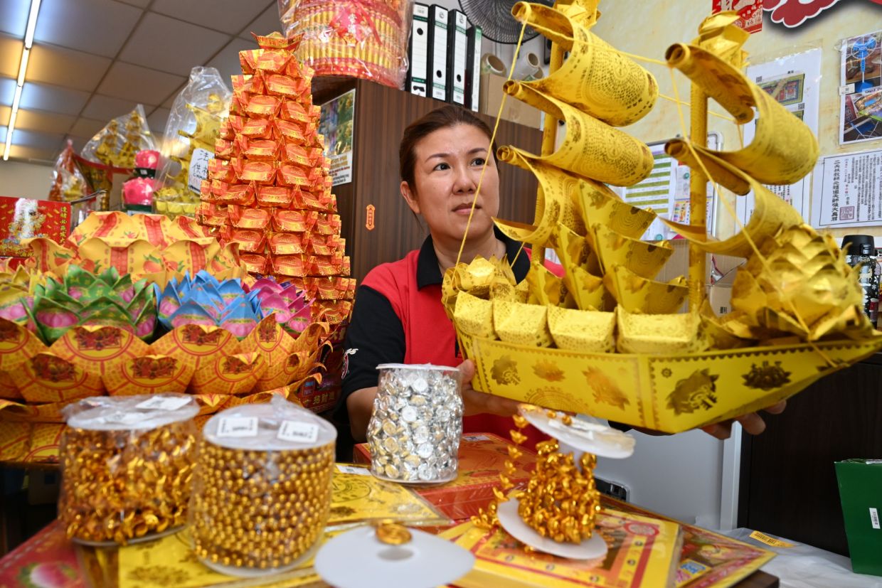 Paraphernalia shop supervisor Ong Hong Ya, 49, showing the various ready made and DIY joss paper and skirting material, that can be used to make custom made (homemade) artful offerings during the Hungry Ghost Festival, at her shop along Jalan Perak, Penang.— K.T.GOH/The Star