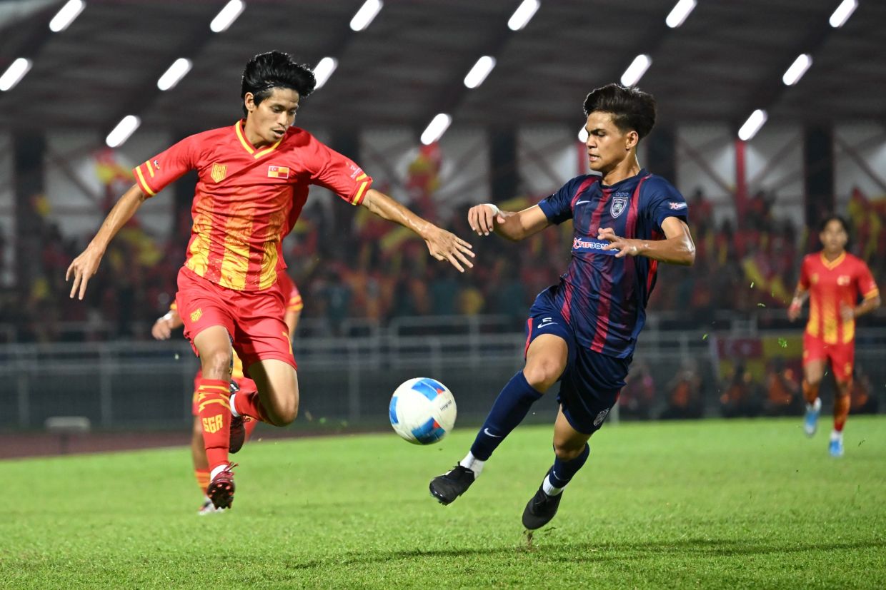 A tussle for the ball between Selangor’s Rohisham Haiqal Hashim (left) and Johor’s Ahmad Lutfil Hadi Sahabudin in the football final match at the Malaysia Games (Sukma). — IZZRAFIQ ALIAS/The Star