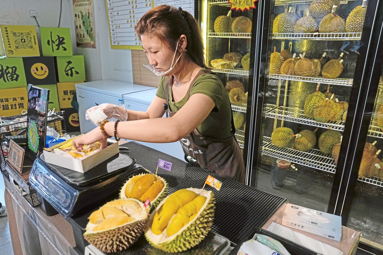 Hou Yuxin packs durian fruit imported from Malaysia for delivery for a customer at a shop in Beijing.