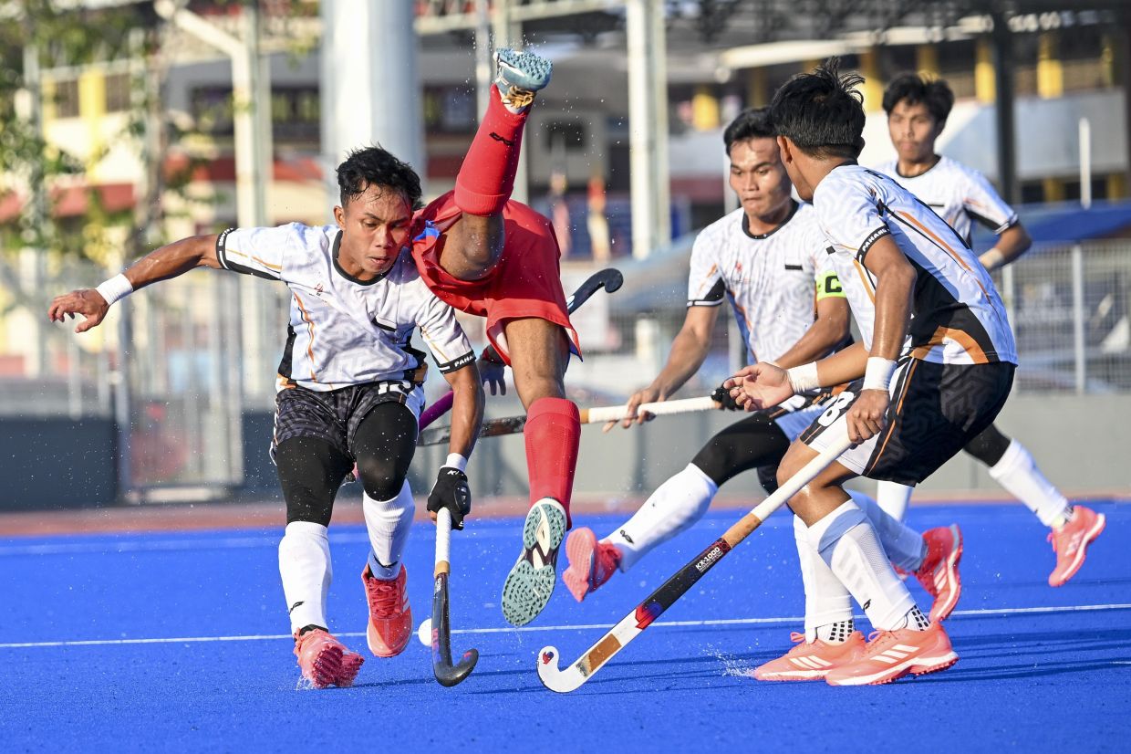 A clashes between Pahang’s Mohd Danish Irfan (left) and Penang’s Kryshant Jiwa Mohan (second left) in the hockey men's Sukma final. — IZZRAFIQ ALIAS/The Star