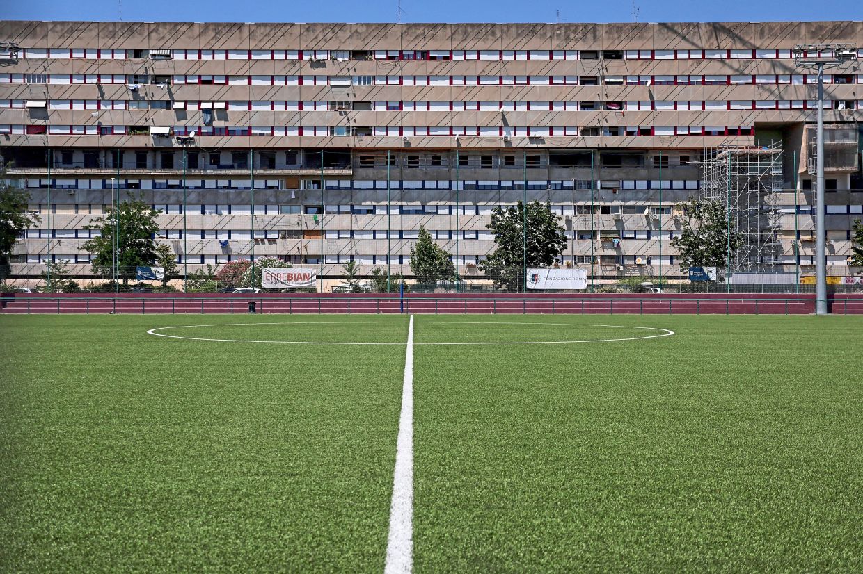 A football pitch stands in front of the Corviale housing complex.
