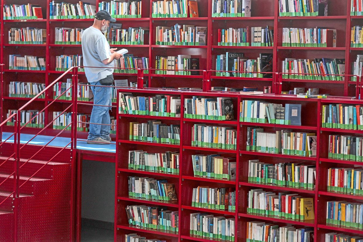 A man looks at a book inside Corviale’s renovated library, which has been turned into a bioclimatic shelter.