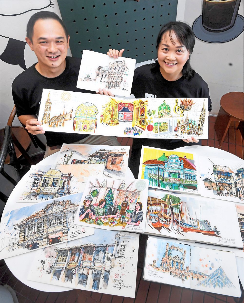 Chua (right) and Tan, founders of Urban Sketchers Klang chapter, showing their artworks of urban scenery locally and abroad.