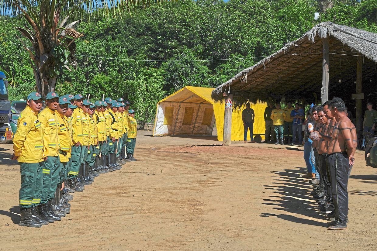 Xerente indigenous firefighters in official fire brigade uniforms (left) and shirtless (right), their bodies marked with traditional painted patterns.
