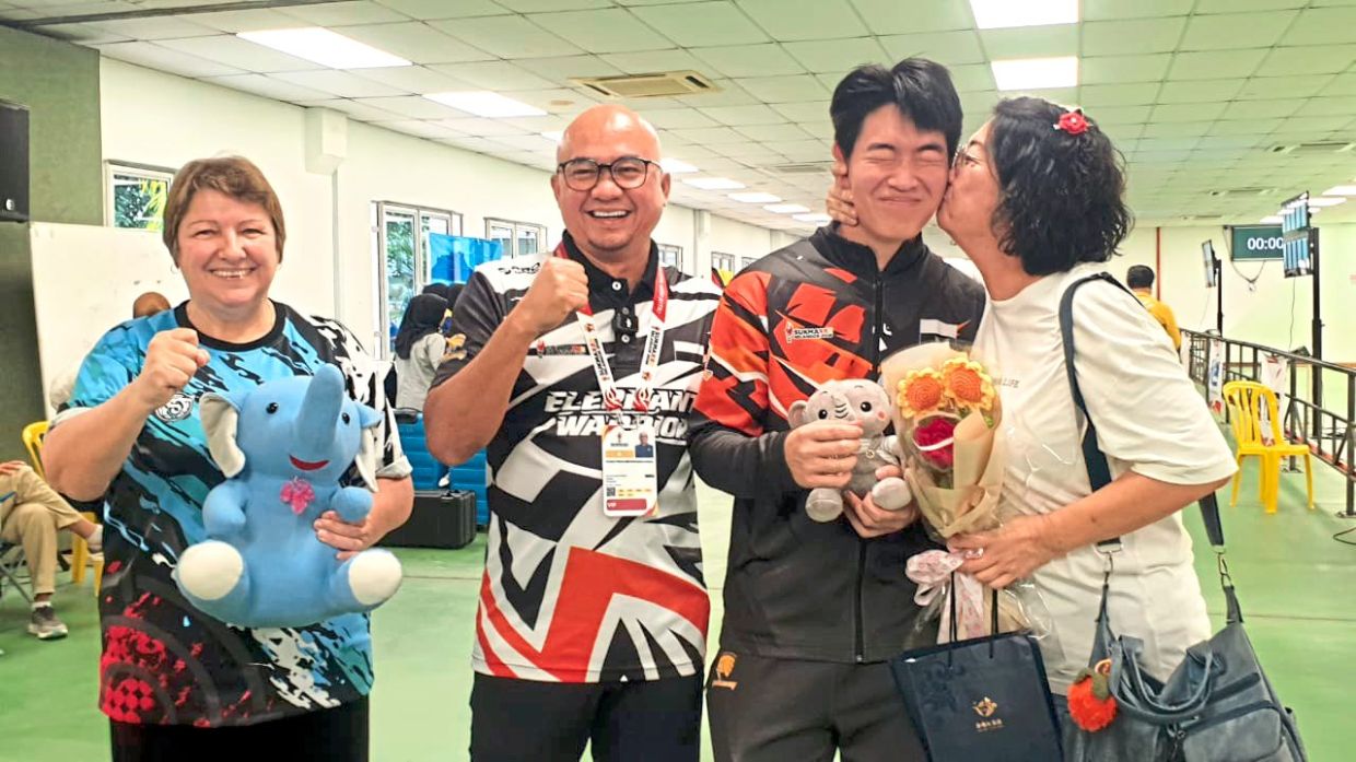 Mummy’s boy: Cheah Zen Hong getting a kiss on his cheek from his mother Helen Bong as coach Elena Sotnik and Pahang exco Datuk Fazli Kamal look on.