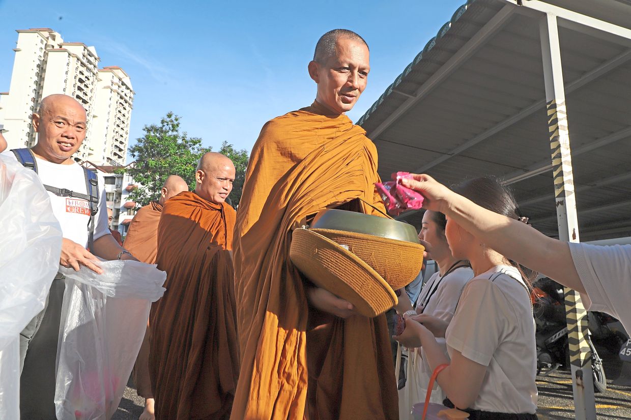 Devotees placing food in monks’ bowls during last year’s event at SMJK Phor Tay in George Town. — Filepic 
