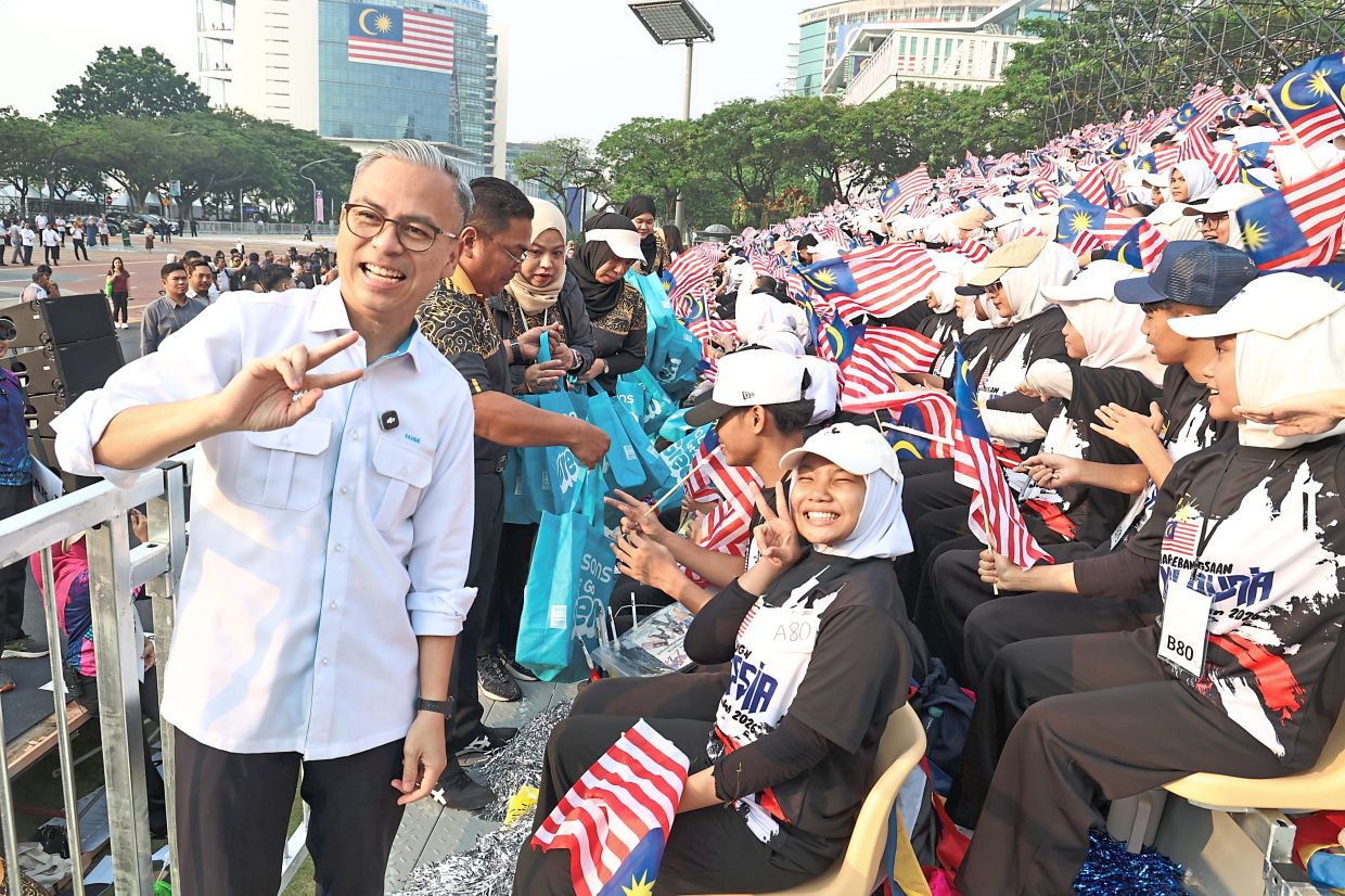 Patriotic boost: Fahmi (left) posing with participants preparing for the National Day celebrations in Putrajaya. — ART CHEN/The Star