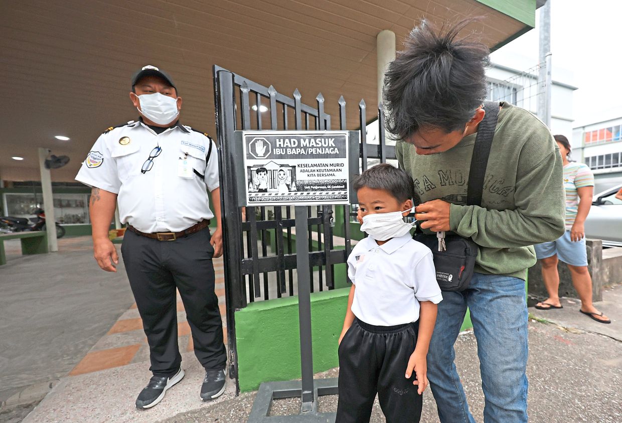 A pupil arriving at SK Combined in Kuching as classes resumed following the temporary closure of schools last Thursday due to worsening haze conditions. — KK SHAM and ZULAZHAR SHEBLEE/The Star