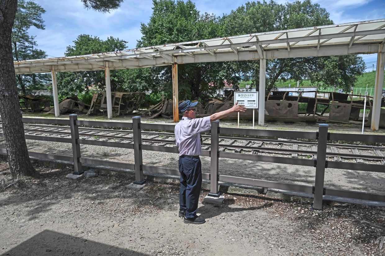 Dreams on pause: A man gesturing while looking at the burnt-out remains of a train carriage at the Woljeong-ri Station in Cheorwon. — AFP