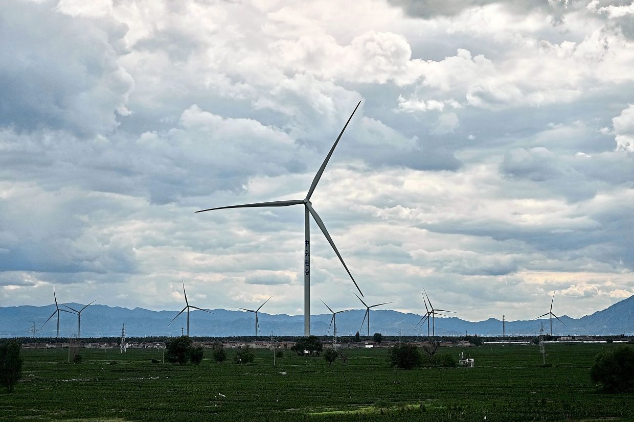 Wind turbines operate along a high speed railway line near Zhangjiakou in northern China’s Hebei province. — AP