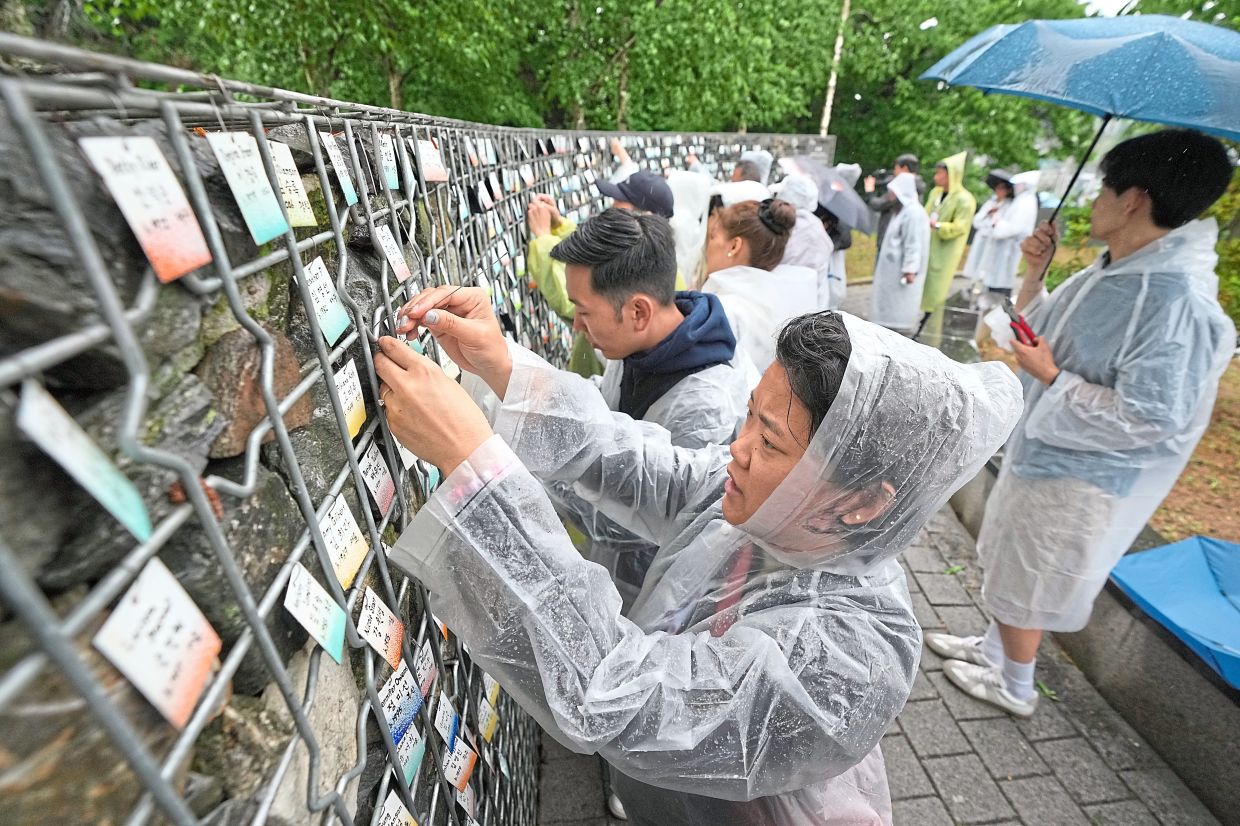 Korean adoptees put their name tags with South Korean volunteers on The Wall of Names at Omma Poom Park in Paju.