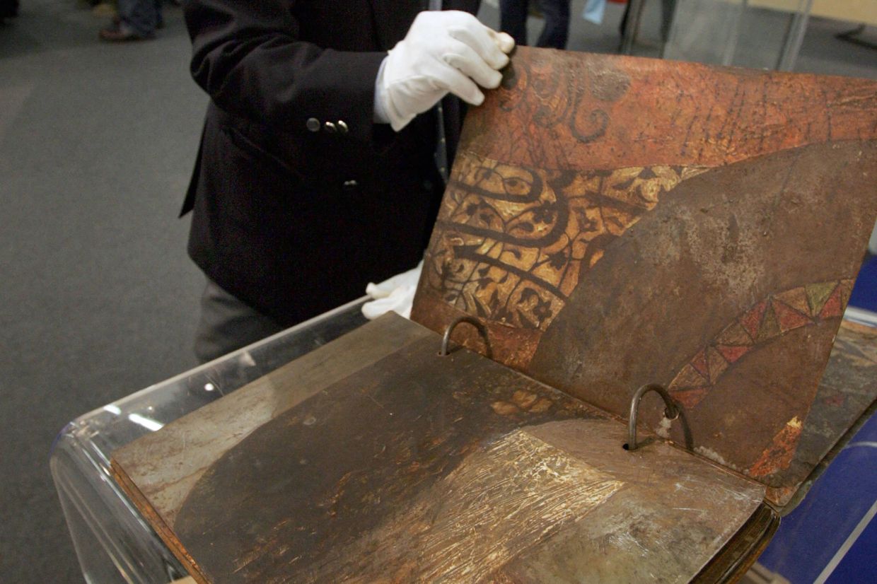 A visitor leafs through artist Sliman Mansour's book 'The Complete Tales Of A Deceased Nobody', made of rusted metal sheets, at the exhibition 'Contemporary Book Art of the Arab World' during the Frankfurt Book Fair in October 2004. Photo: AFP 