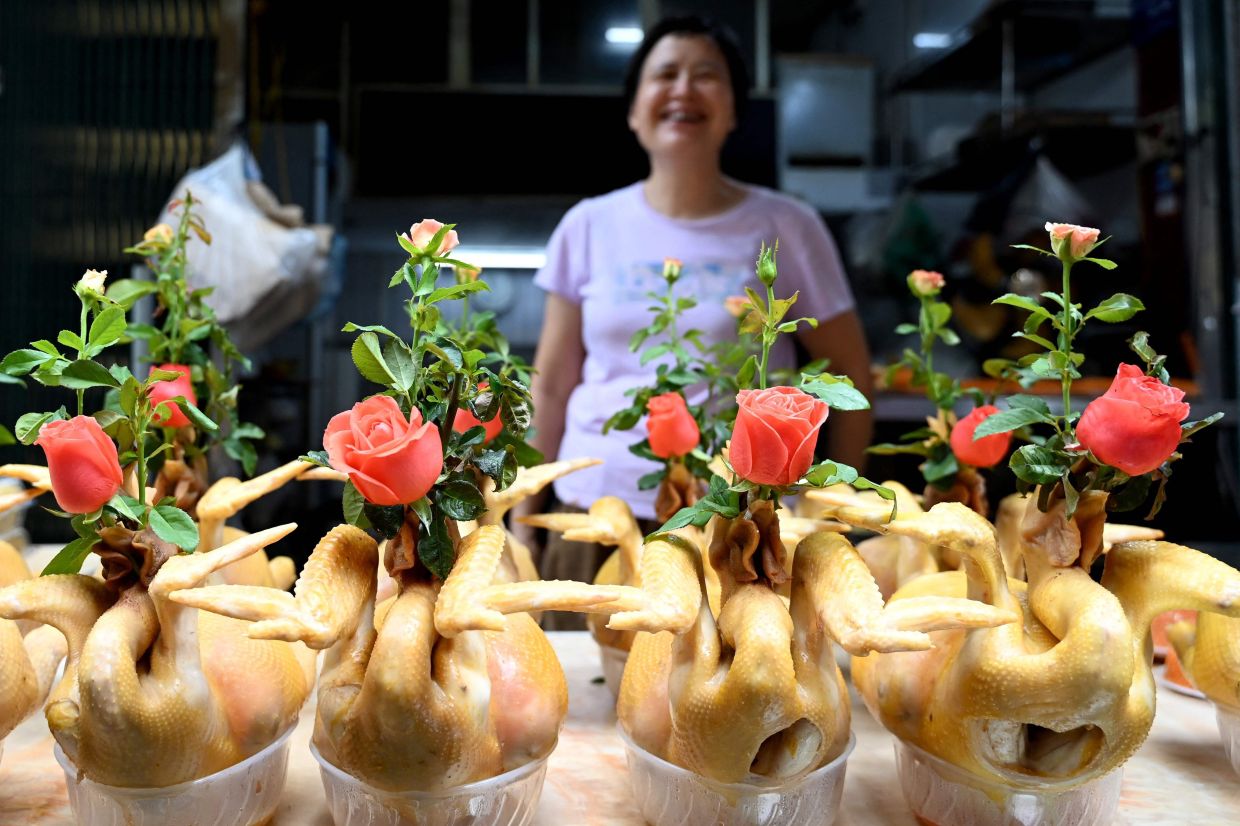 A cooked boiled chicken vendor waits for customers at her shop in Hanoi on August 25, 2026. - AFP