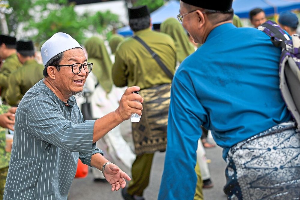 Scent-sational gesture: Resident Rosman Sabdin, 60, voluntarily spraying perfume on parade participants during the Malacca State-level Maulidur Rasul celebration in Bukit Baru, Melaka. Approximately 101 contingents involving nearly 7,000 participants joined the parade, marching from Stadium Tun Fatimah in Bukit Serindit to the Dataran Pusat Islam in Bukit Baru. — Bernama