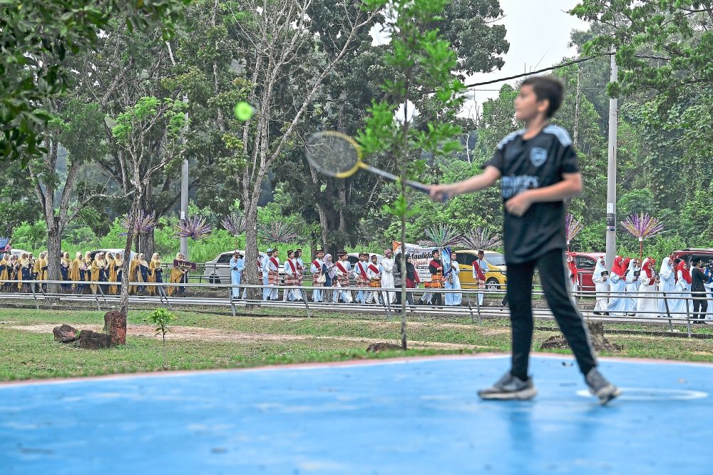 Colourful procession: (Above and below) Participants taking part in the Sungai Petani Parliamentary-level Maulidur Rasul celebration parade at Masjid Kariah Bandar Perdana, as a boy plays badminton in the foreground. The 2.4km parade involved 36 contingents comprising various agencies and organisations, as well as secondary and primary schools. — Bernama