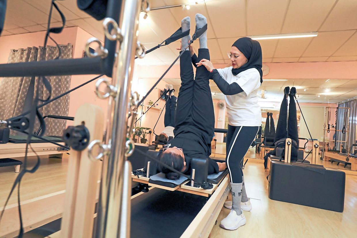 Maslinda correcting the posture of a student during a class.
